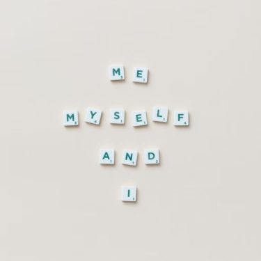 Minimalist composition of Scrabble tiles spelling 'Me, Myself, and I' on a white background.